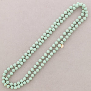 Turquoise beaded necklace on a light pink background