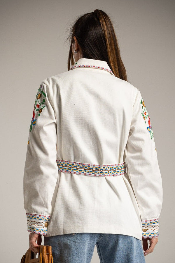 Person wearing a white jacket with colorful patterns on a gray background