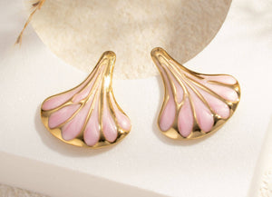 Gold and pink earrings in a jewelry box with delicate gold thread.