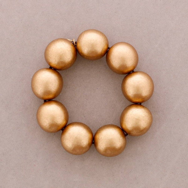 A beaded bracelet made of eight large, round, metallic gold beads arranged in a circle on a neutral gray background.
