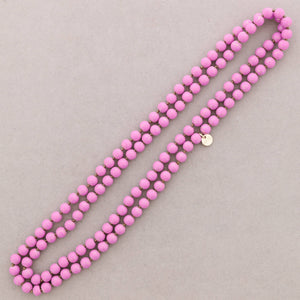Pink beaded necklace on a light gray background