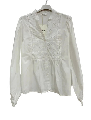 White blouse with lace details on a hanger against a white background