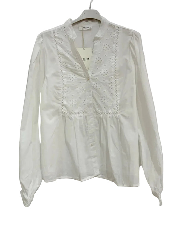 White blouse with lace details on a hanger against a white background