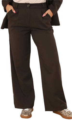 Person wearing brown wide-leg pants with a plain background