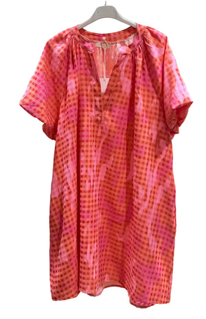 Orange and pink patterned dress on a hanger against a white background