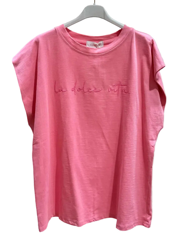 Pink t-shirt with 'la dolce vita' text on a hanger against a plain background