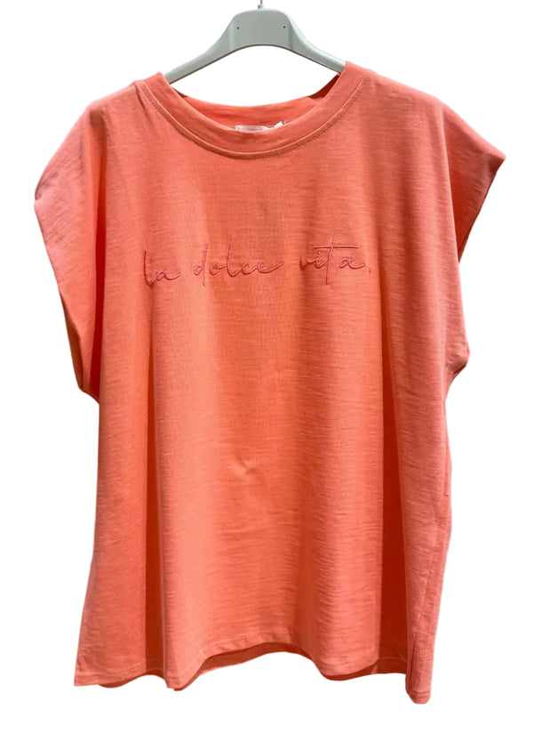 Coral t-shirt with text on a hanger against a plain background