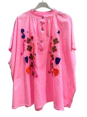 Pink shirt with colorful embroidered designs on a white background