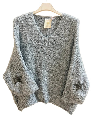 A chunky knit, textured grey sweater with three-quarter sleeves and dark embroidered star details on the cuffs.