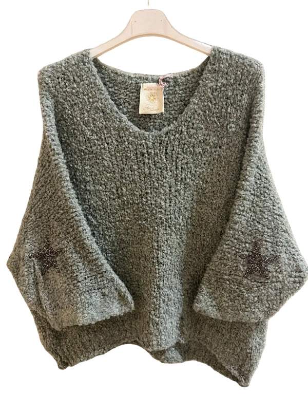 A chunky knit, textured sage green sweater with three-quarter sleeves and dark embroidered star details on the cuffs.