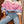 Load image into Gallery viewer, A woman seated indoors wearing a fuzzy knit cardigan with horizontal stripes in cream, pink, and light purple, paired with light blue jeans and a brown belt.
