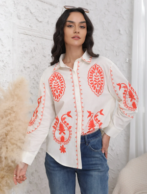 Woman wearing a white blouse with red floral patterns against a white background
