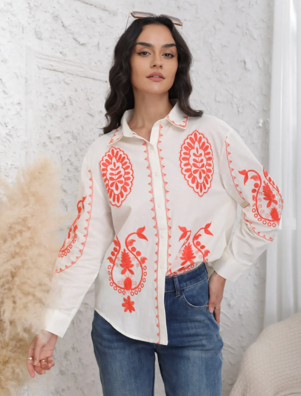 Woman wearing a white blouse with red floral patterns against a white background