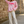 Load image into Gallery viewer, Woman wearing a pink sweatshirt with 'ICONIC' text, white pants, and white sneakers standing against a stone wall.
