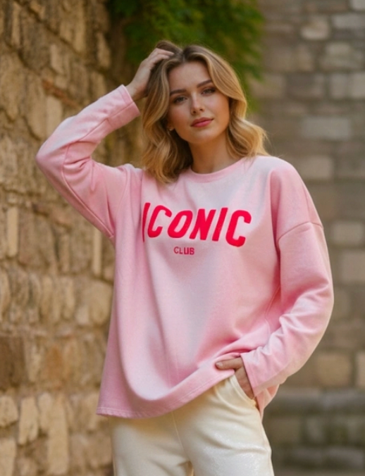 Woman wearing a pink sweatshirt with 'ICONIC' club text