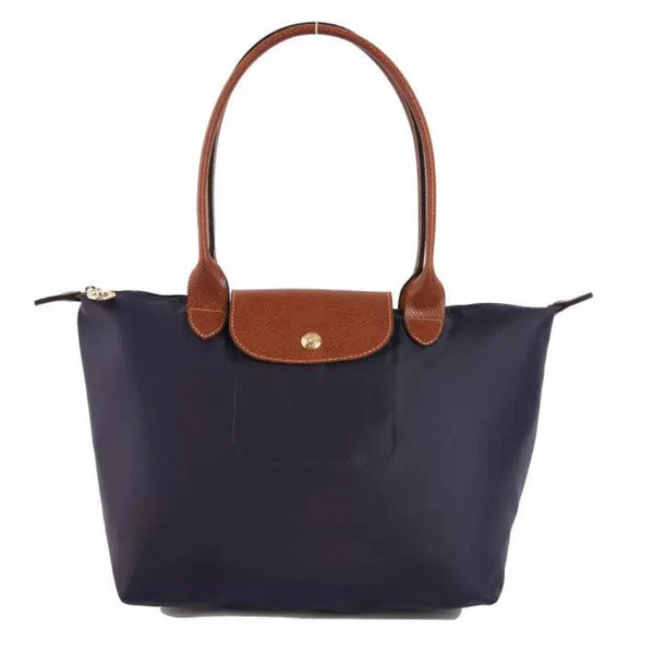 Navy blue handbag with brown leather handles and flap on a white background
