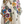 Load image into Gallery viewer, A cream-colored short-sleeve button-up shirt with a vibrant multicolor floral and leaf pattern, displayed on a mannequin torso against a plain light gray background.
