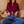 Load image into Gallery viewer, Front view of a woman wearing a women's burgundy fine-knit mock-neck zip-up cardigan with white contrast racing stripes down the sleeves, styled with blue high-waisted jeans.
