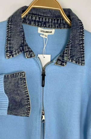 A light blue knit zip-up sweater with a denim collar and a denim chest pocket, hanging on a wooden hanger. The brand name 'LIZABELLE' is visible on the neck label.