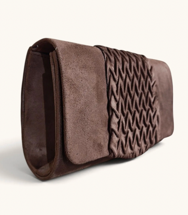 A dark brown suede clutch bag with a textured, braided wavy pattern panel on the front, shown against a plain off-white background.