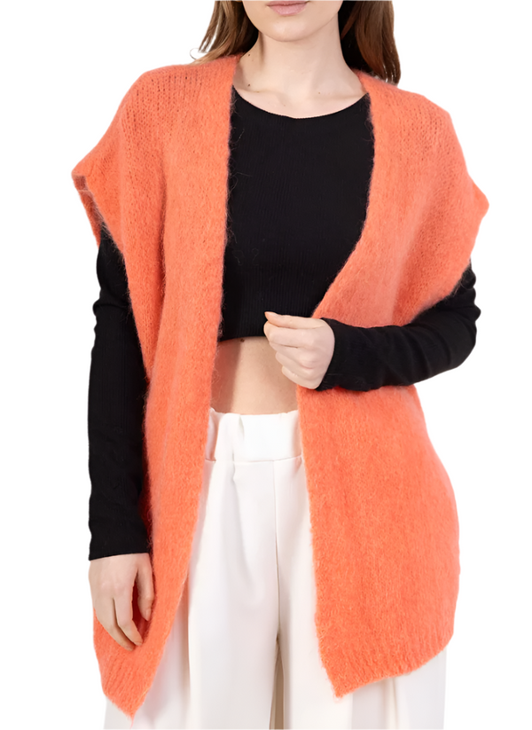 Person wearing an coral cardigan over a black top and white pants on a white background
