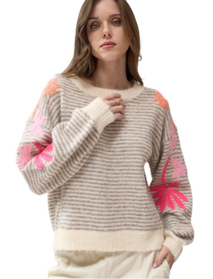 Woman wearing a sweater with pink floral emroidered patterns on the sleeve 