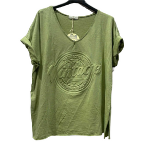 Olive Green t-shirt with 'Vintage' logo on a hanger against a white brick wall.