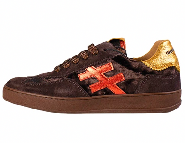 Another Trend sneaker in dark brown suede with a metallic gold heel tab, brown laces, a brown rubber sole, and a prominent orange-red embroidered cross logo on the side.