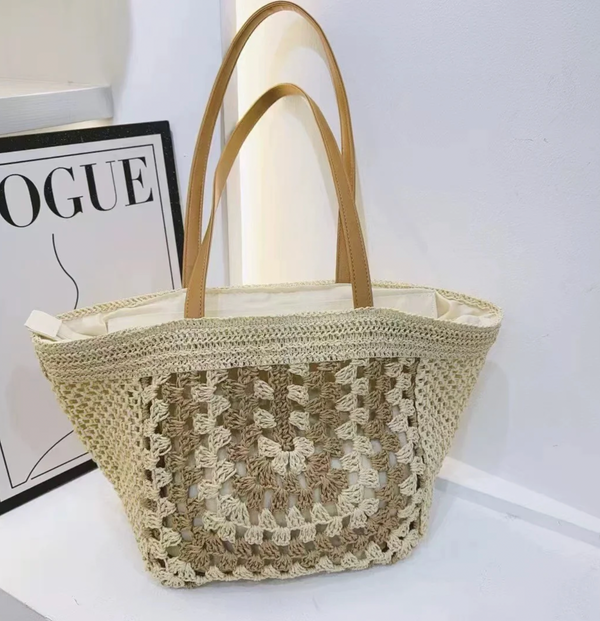 Woven handbag with beige handles on a white surface