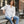 Load image into Gallery viewer, Woman sitting on a bench wearing a white blouse and blue jeans in an urban setting.
