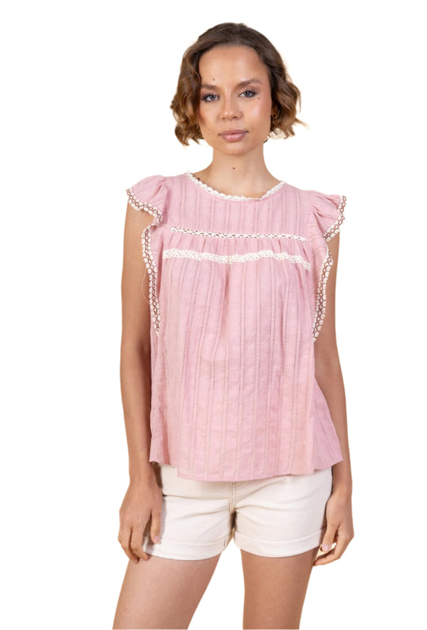 Woman wearing a pink blouse with ruffled sleeves on a beige background