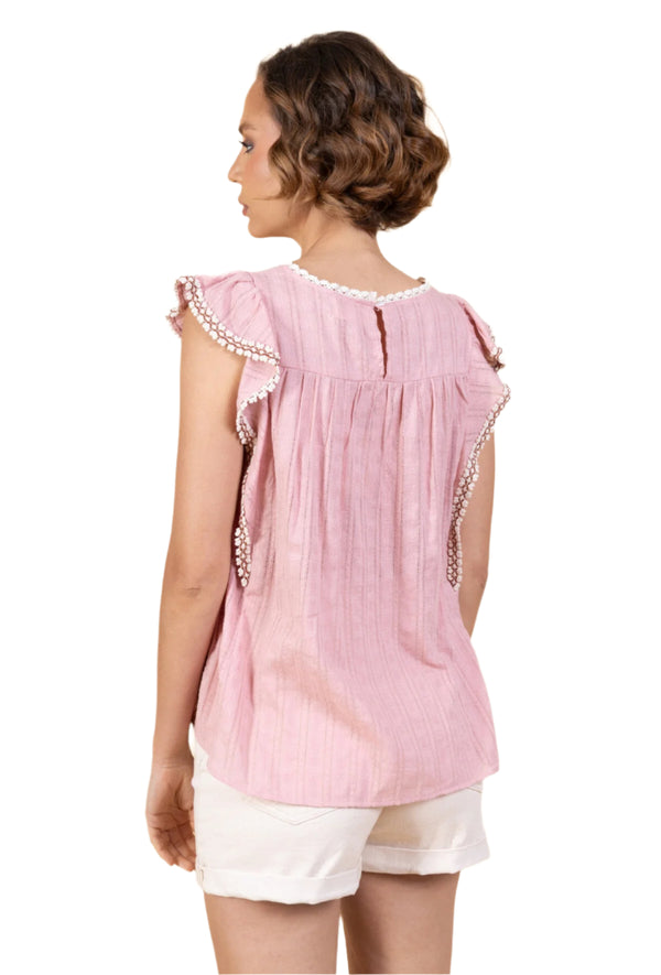 Woman wearing a pink blouse with white trim on a beige background