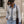 Load image into Gallery viewer, Front view of a woman wearing a grey  fine-knit button-up cardigan featuring a contrast light-wash denim collar, placket, and layered cuffs, finished with polished gold dome buttons and styled with white pants
