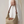 Load image into Gallery viewer, Beige handbag with brown leather accents held by a person wearing a white dress.
