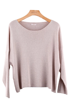 Beige sweater on a wooden hanger against a pink tiled wall