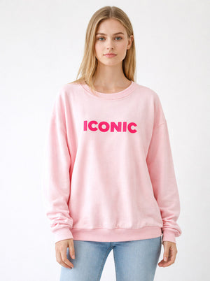 Person wearing a pink sweatshirt with 'ICONIC' text on a white background